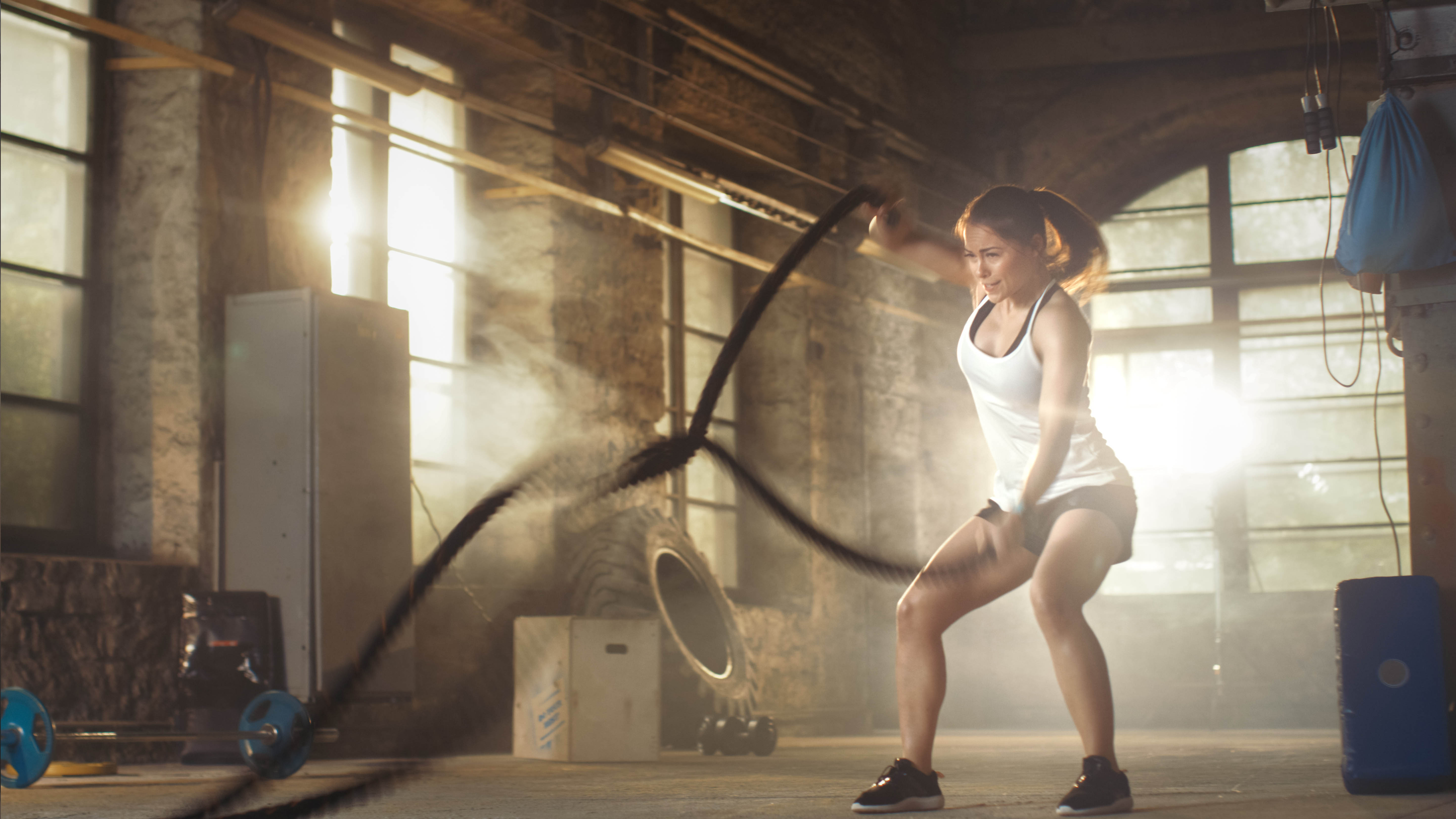Strong, fit woman using the battle ropes for a workout in a gym Strong, fit woman using the battle ropes for a workout in a gym